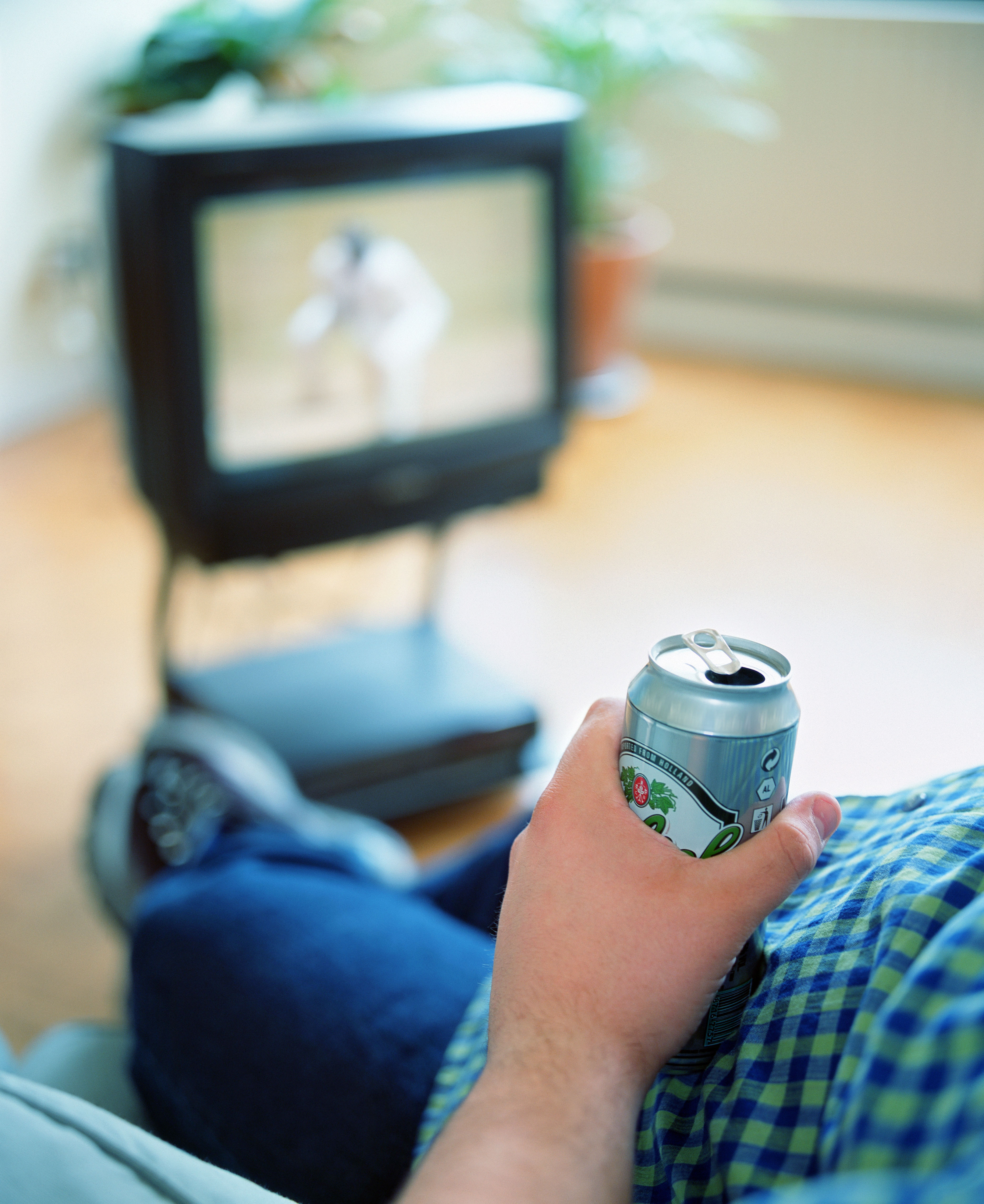 Man with beer can watching television